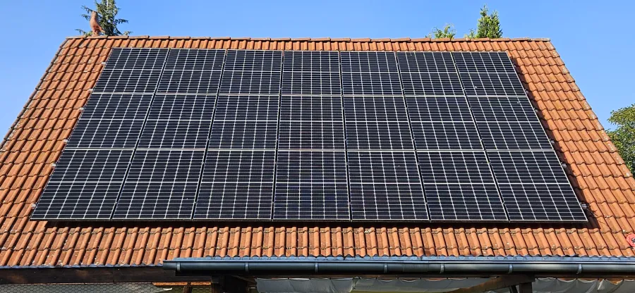 Einfamilienhaus mit Photovoltaik, umgeben von Baumbestand